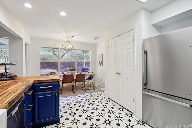 kitchen with wood counters, blue cabinetry, stainless steel appliances, light flooring, and a chandelier