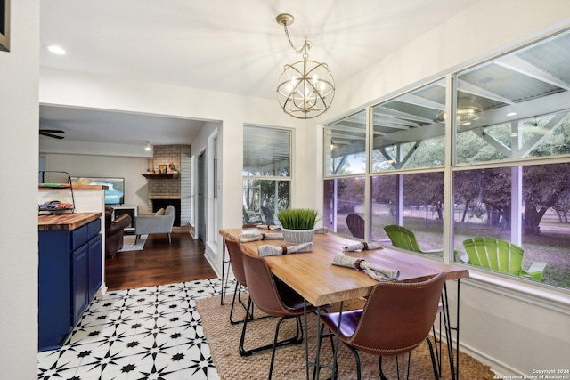 dining room with light flooring, a brick fireplace, and a chandelier