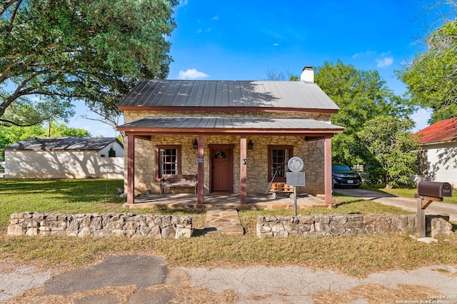 1213 Isabella, Castroville, TX 78009 - view of front of home with stone siding, a porch, a chimney, metal roof, and a front lawn