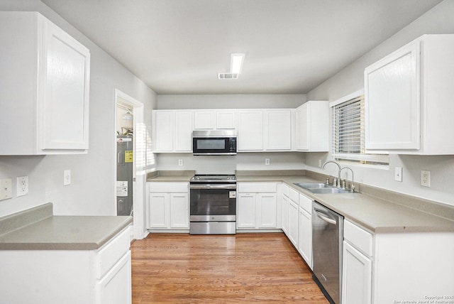 135 Blue Juniper, San Antonio, TX 78253 - kitchen featuring stainless steel appliances, a sink, white cabinets, and light wood-type flooring