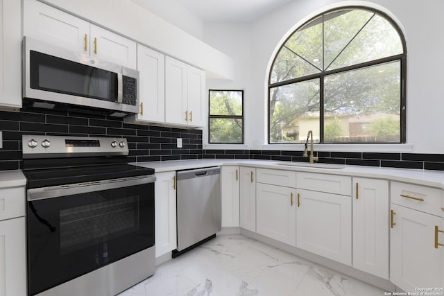 16726 Burning Glade, San Antonio, TX 78247 - kitchen with stainless steel appliances, a sink, light marble finish floors, white cabinets, and tasteful backsplash