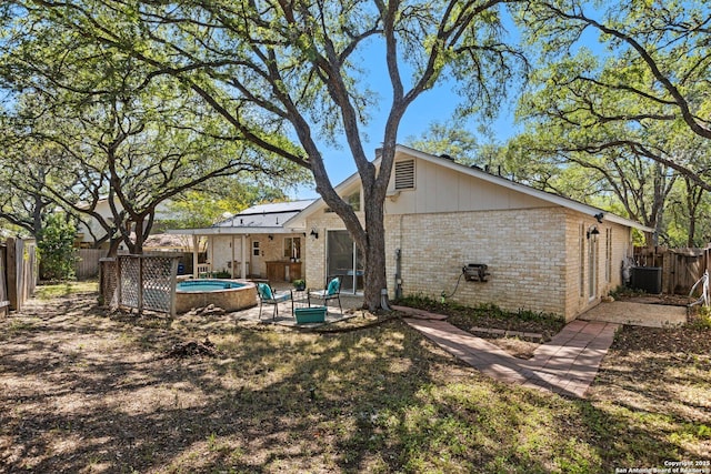 13018 Country Trl, San Antonio, TX 78216 - rear view of house with a fenced backyard, brick siding, roof mounted solar panels, central AC, and a patio