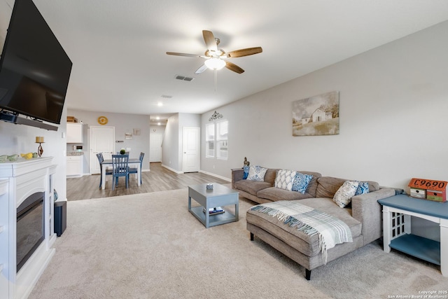 14383 Palm Rdg, San Antonio, TX 78253 - living area featuring ceiling fan, a glass covered fireplace, light carpet, light wood-style flooring, and baseboards