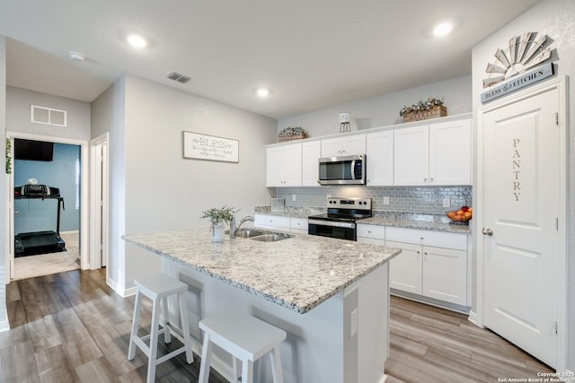 14383 Palm Rdg, San Antonio, TX 78253 - kitchen with stainless steel appliances, a sink, light wood-style floors, an island with sink, and white cabinetry