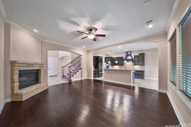 523 White Cyn, San Antonio, TX 78260 - unfurnished living room featuring arched walkways, a ceiling fan, light wood-style flooring, a stone fireplace, and crown molding