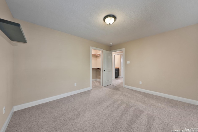 523 White Cyn, San Antonio, TX 78260 - unfurnished bedroom featuring light colored carpet, a walk in closet, baseboards, and a textured ceiling