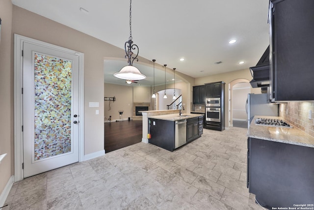 523 White Cyn, San Antonio, TX 78260 - kitchen with appliances with stainless steel finishes, arched walkways, an island with sink, backsplash, and decorative light fixtures