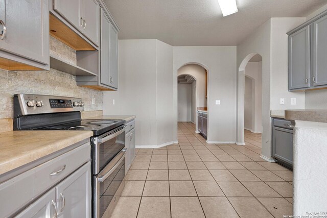 6818 Sabine Pass, San Antonio, TX 78242 - kitchen with double oven range, gray cabinets, arched walkways, and baseboards