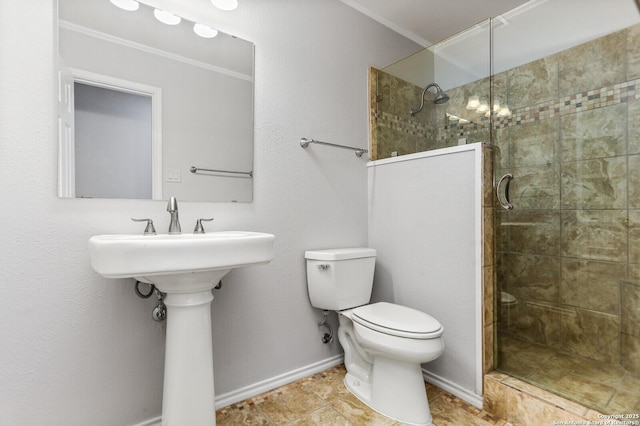 bathroom featuring tiled shower, ornamental molding, toilet, a sink, and baseboards