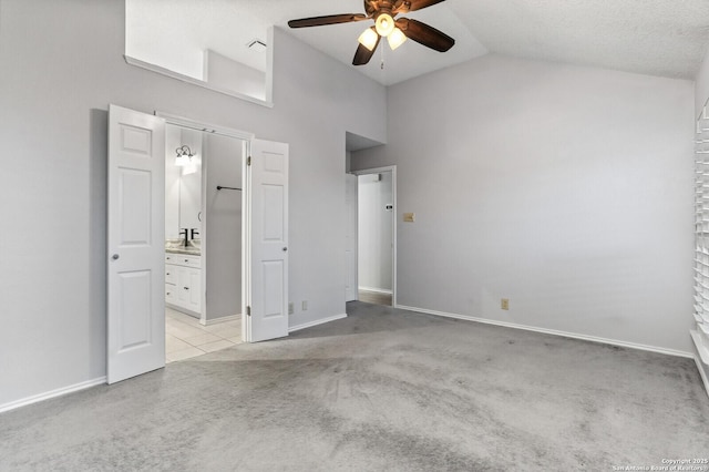 unfurnished bedroom with light colored carpet, high vaulted ceiling, ensuite bathroom, ceiling fan, and baseboards