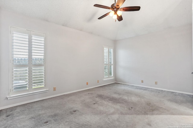 carpeted empty room featuring ceiling fan, vaulted ceiling, and baseboards