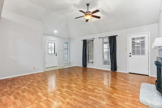 unfurnished living room featuring lofted ceiling, ceiling fan, light wood-type flooring, and baseboards