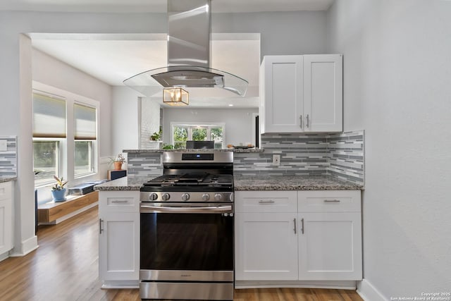944 Fulton, San Antonio, TX 78201 - kitchen with stainless steel gas range oven, island range hood, backsplash, white cabinetry, and light stone counters