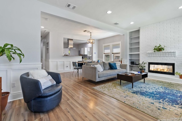944 Fulton, San Antonio, TX 78201 - living room with wood finished floors, built in features, a brick fireplace, a wainscoted wall, and recessed lighting
