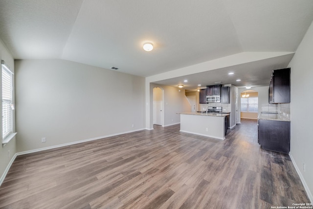 12358 Erstein, Selma, TX 78154 - unfurnished living room featuring vaulted ceiling, arched walkways, dark wood-type flooring, baseboards, and recessed lighting