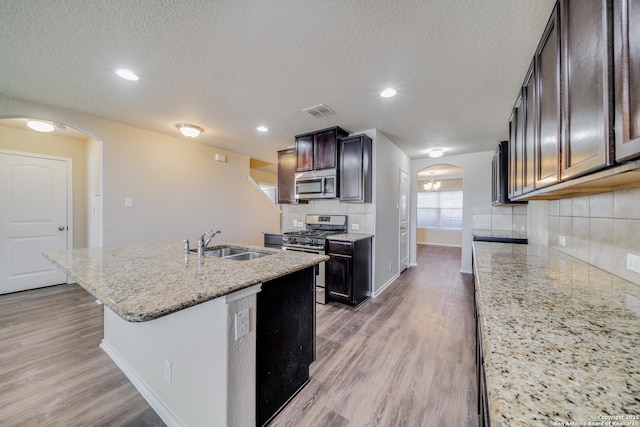 12358 Erstein, Selma, TX 78154 - kitchen with appliances with stainless steel finishes, a sink, arched walkways, baseboards, and light wood-type flooring