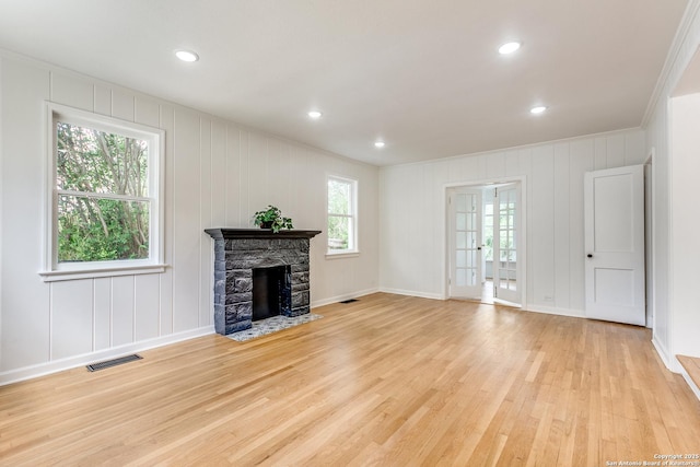 123 W Mandalay, San Antonio, TX 78212 - unfurnished living room featuring light wood-style floors, crown molding, a stone fireplace, a decorative wall, and baseboards