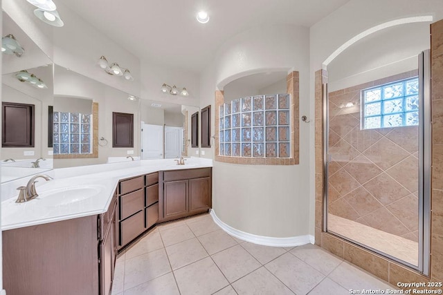 bathroom with tiled shower, tile patterned flooring, and double vanity