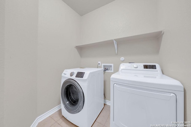 laundry area with washing machine and dryer, light tile patterned flooring, and baseboards