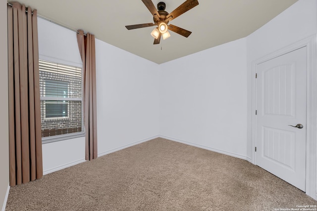 carpeted spare room with a ceiling fan and baseboards