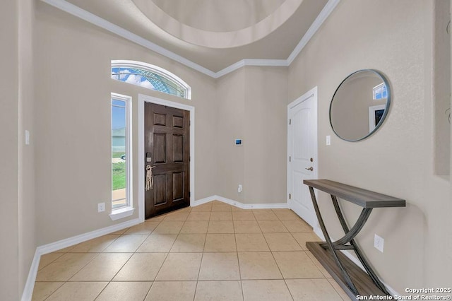 foyer with healthy amount of natural light, ornamental molding, light tile patterned flooring, and baseboards