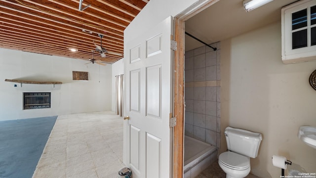 217 Sky View Dr, Adkins, TX 78101 - full bath with ceiling fan, tiled shower, toilet, and a glass covered fireplace