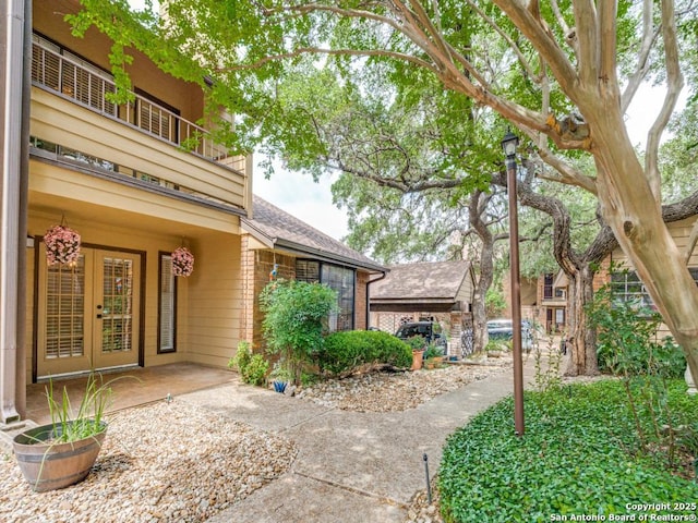 3605 Hidden Unit E1, San Antonio, TX 78217 - entrance to property featuring a balcony, french doors, a shingled roof, and brick siding
