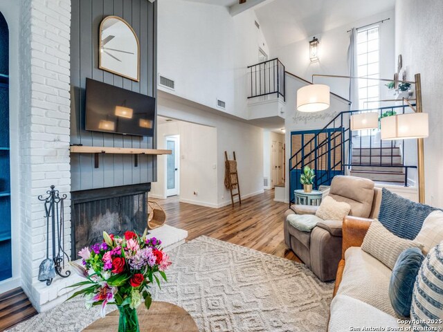 3605 Hidden Unit E1, San Antonio, TX 78217 - living area with wood finished floors, stairs, beamed ceiling, high vaulted ceiling, and a brick fireplace