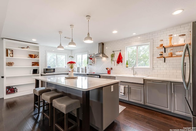 9811 Rebel Queen, San Antonio, TX 78255 - kitchen featuring wall chimney range hood, a sink, freestanding refrigerator, a kitchen island, and a breakfast bar area