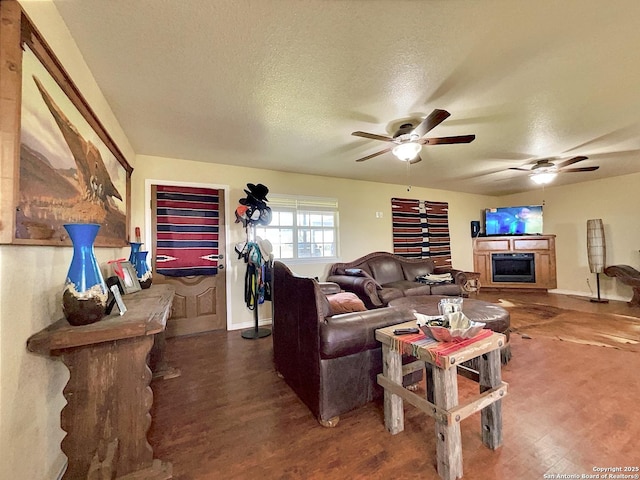 3389 Fm 888, Beeville, TX 78102 - living area featuring a ceiling fan, a fireplace, wood finished floors, a textured ceiling, and baseboards