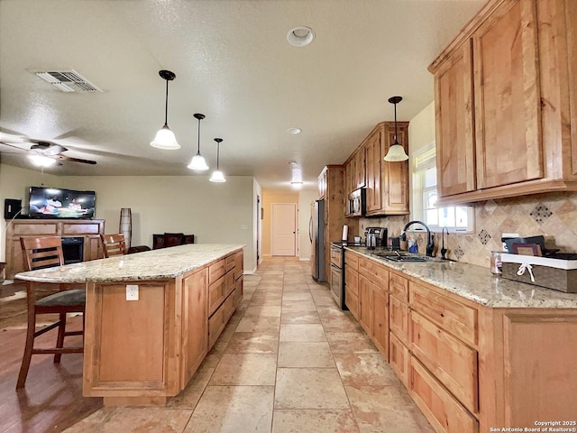3389 Fm 888, Beeville, TX 78102 - kitchen featuring a sink, appliances with stainless steel finishes, a kitchen island, a kitchen breakfast bar, and light stone countertops
