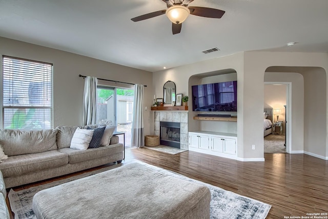 1227 Sun Spg, San Antonio, TX 78245 - living room with wood finished floors, a ceiling fan, baseboards, a fireplace, and arched walkways
