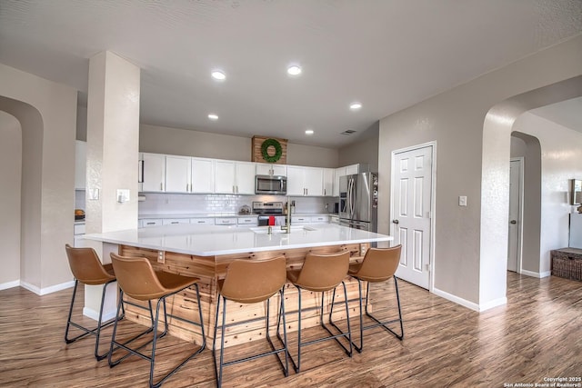 1227 Sun Spg, San Antonio, TX 78245 - kitchen featuring appliances with stainless steel finishes, wood finished floors, decorative backsplash, arched walkways, and light countertops