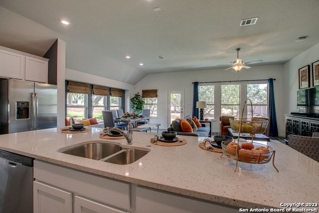 8907 Turkey Crk, Seguin, TX 78155 - kitchen featuring stainless steel appliances, open floor plan, a sink, white cabinetry, and light stone counters