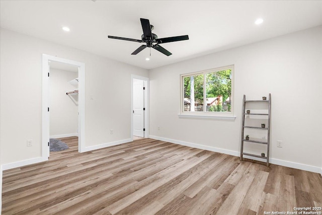 unfurnished bedroom featuring light wood finished floors, recessed lighting, baseboards, ceiling fan, and a spacious closet