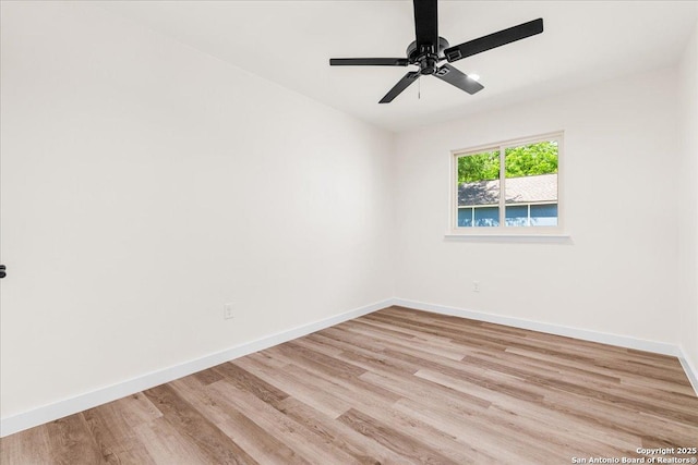 spare room with baseboards, light wood-style floors, and ceiling fan