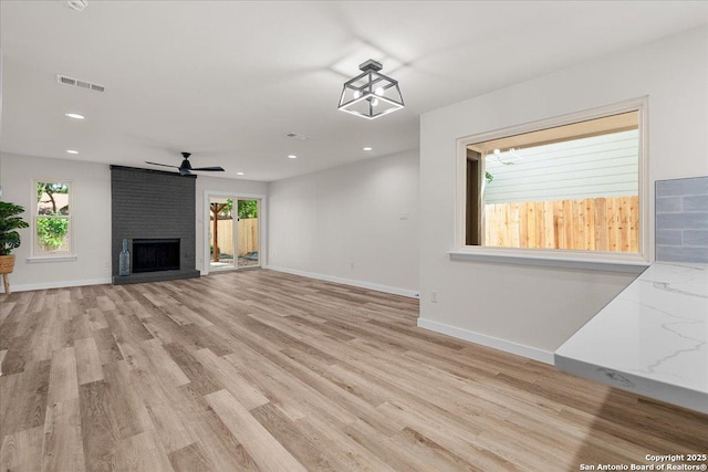 unfurnished living room featuring light wood-type flooring, a brick fireplace, recessed lighting, baseboards, and a ceiling fan
