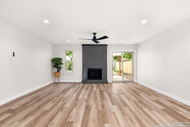 unfurnished living room featuring light wood-style flooring, a brick fireplace, a ceiling fan, recessed lighting, and baseboards