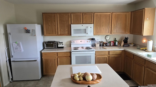 9406 Vallecito Pass, San Antonio, TX 78250 - kitchen with white appliances, light tile patterned floors, light countertops, and brown cabinets