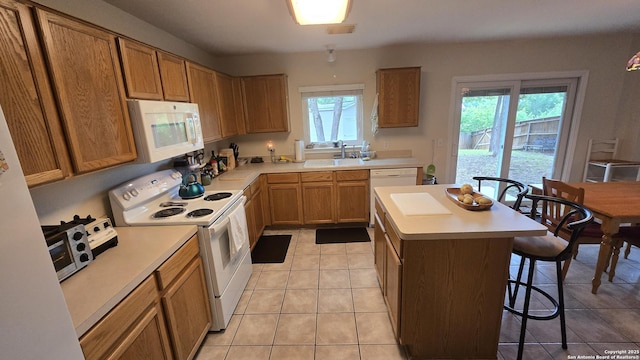 9406 Vallecito Pass, San Antonio, TX 78250 - kitchen featuring white appliances, a breakfast bar, healthy amount of natural light, and light countertops