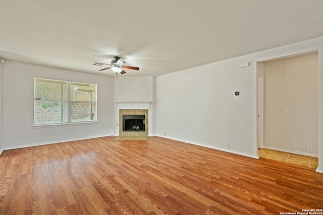 15603 Hastings Park, Selma, TX 78154 - unfurnished living room with a ceiling fan, light wood-style flooring, a tile fireplace, and baseboards