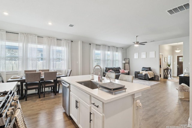 kitchen featuring a sink, ceiling fan, white cabinets, wood finished floors, and a kitchen island with sink