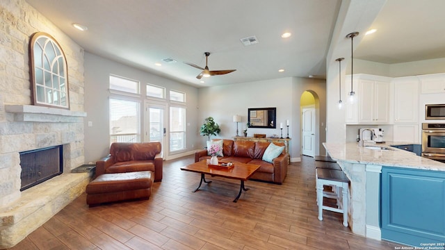 2542 Varrelmann, New Braunfels, TX 78132 - living room featuring a ceiling fan, a stone fireplace, arched walkways, wood finished floors, and recessed lighting