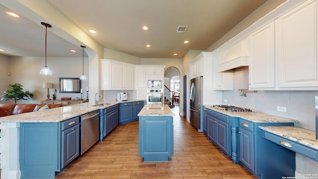 2542 Varrelmann, New Braunfels, TX 78132 - kitchen featuring blue cabinetry, appliances with stainless steel finishes, arched walkways, light wood-style floors, and white cabinetry
