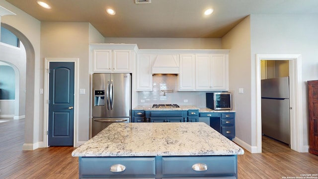 2542 Varrelmann, New Braunfels, TX 78132 - kitchen featuring stainless steel appliances, blue cabinetry, arched walkways, light wood-style floors, and recessed lighting