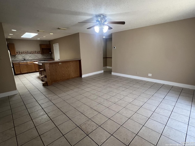 15558 Knollmeadow, San Antonio, TX 78247 - kitchen featuring open floor plan, a peninsula, backsplash, a ceiling fan, and a textured ceiling