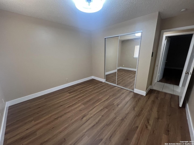 15558 Knollmeadow, San Antonio, TX 78247 - unfurnished bedroom with dark wood finished floors, a closet, baseboards, and a textured ceiling