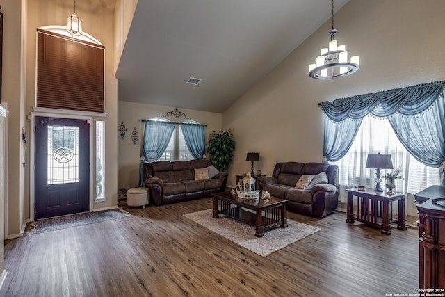 living room featuring wood finished floors, high vaulted ceiling, a chandelier, and baseboards