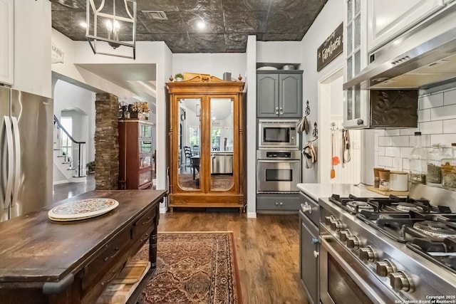 111 Kendall Oaks, Boerne, TX 78006 - kitchen with appliances with stainless steel finishes, under cabinet range hood, dark wood-style floors, tasteful backsplash, and an ornate ceiling