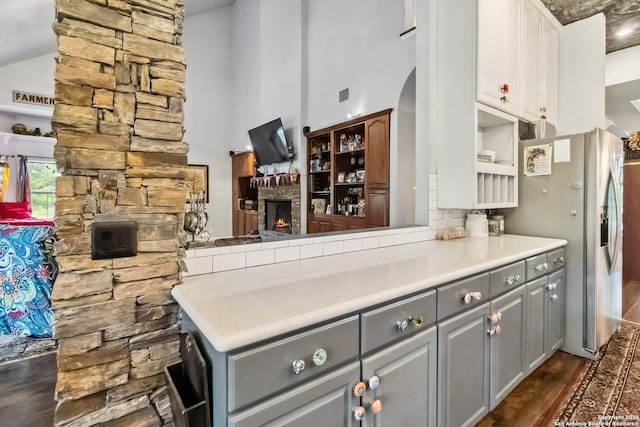 111 Kendall Oaks, Boerne, TX 78006 - kitchen with gray cabinets, a towering ceiling, a lit fireplace, stainless steel fridge, and white cabinetry